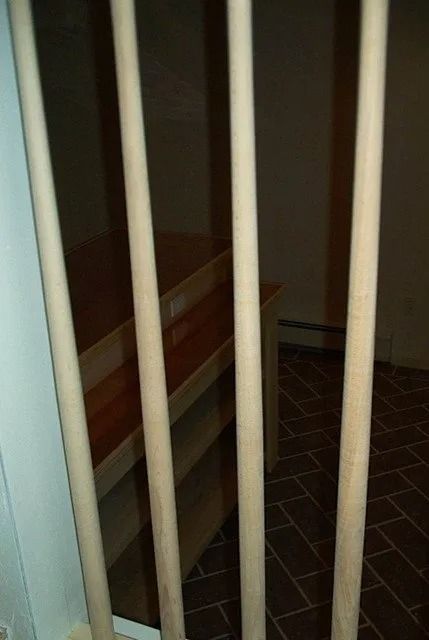 Vertical white bars in a dim hallway, partially blocking a tiled floor and wall.