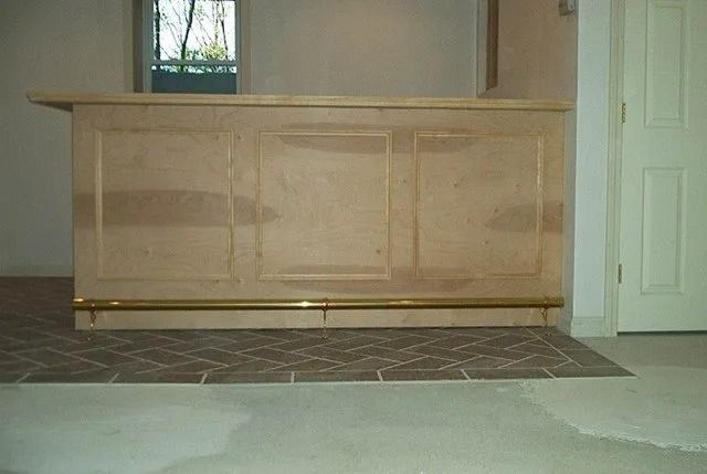 Empty lobby with a light wood reception counter, tiled floor, and a closed white door.