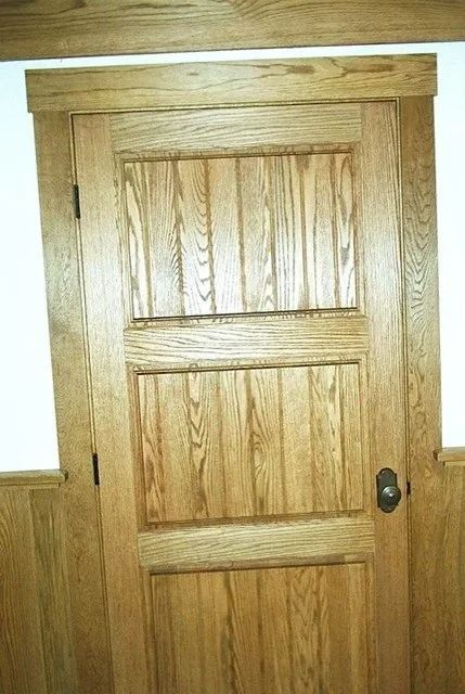 Wooden interior door with vertical panels and a dark round knob.