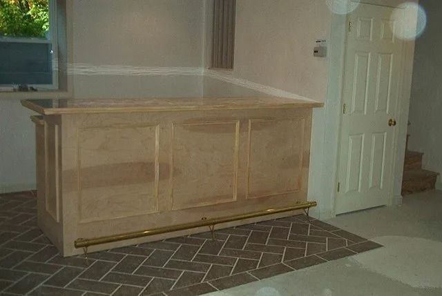 Wooden cabinet or built-in bar in a beige room beside a white door and patterned rug