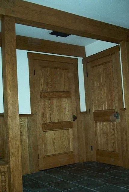Wood-paneled hallway with two closed wooden doors and dark tile flooring