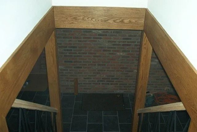Stairwell landing with wood railings and a brick wall at the end, viewed from above