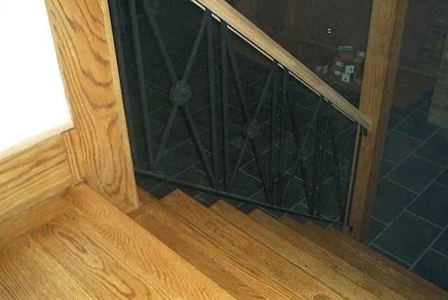 Wooden stairs beside a black metal gate or door in a home interior