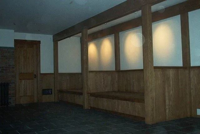 Empty wood-paneled room with frosted window panels and a bench along the wall