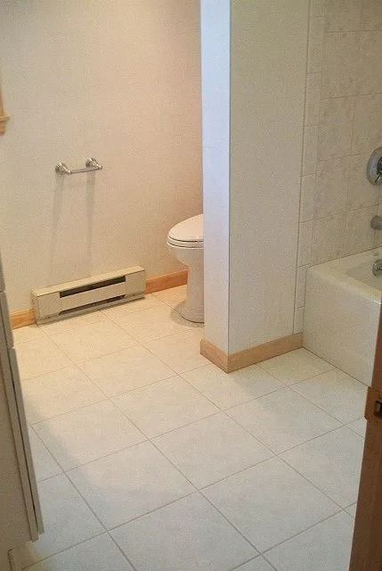 Small tiled bathroom with a toilet, sink, and bathtub partially visible.