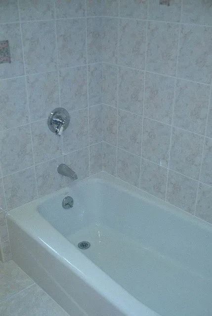 Bathtub with tiled shower wall and chrome faucet in a bathroom