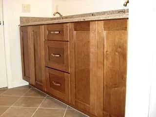 Wooden bathroom vanity with granite countertop, sink, and two drawers in a tiled room