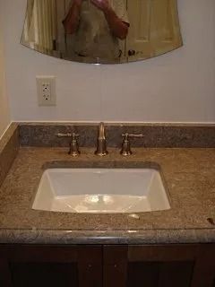 Bathroom sink with granite countertop, chrome faucet, and mirror above.