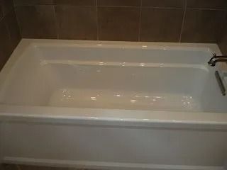 White bathtub with built-in seat and chrome faucet against brown tiled bathroom wall