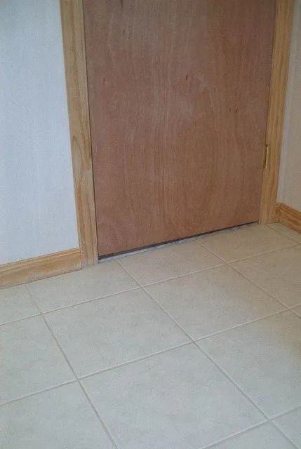 Closed wooden door in a tiled room with light-colored walls and wood trim