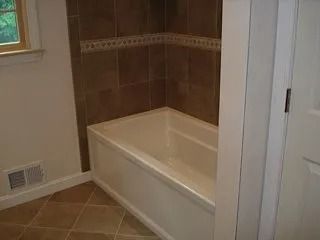 Corner bathtub with beige tile surround in a bathroom