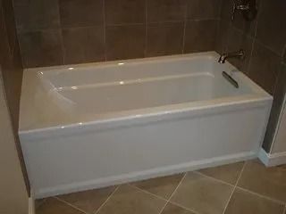 White bathtub in a brown-tiled bathroom corner