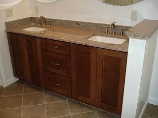 Brown bathroom vanity with double sinks and granite countertop on tile floor