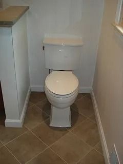Small bathroom with a white toilet and tan tile floor.