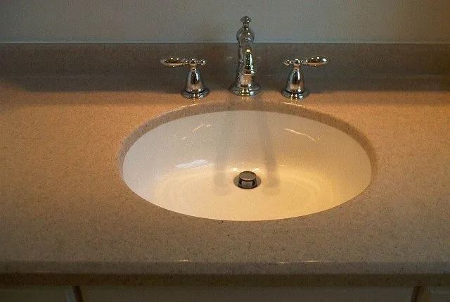 Bathroom sink with chrome faucet and beige countertop