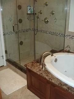 Bathroom with glass shower enclosure, corner jetted tub, and granite vanity counter