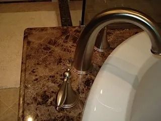 Marble bathroom countertop with a chrome faucet and white sink basin