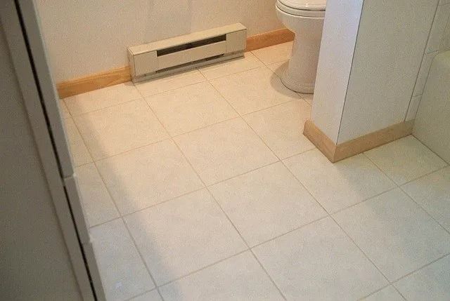 Small tiled bathroom with a toilet and a wall-mounted heater.