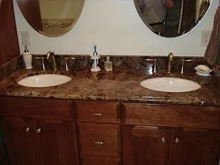 Double bathroom vanity with marble countertop, two sinks, mirrors, and dark wood cabinets.