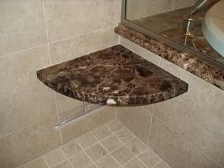 Corner marble shower bench with a clear support leg and beige tiled walls and floor