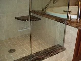 Glass shower enclosure beside a bathtub in a tiled bathroom