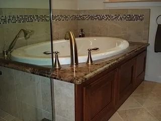 Bathroom vanity with a white oval sink, bronze faucet, granite countertop, and tiled backsplash