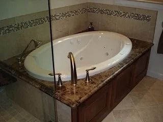 Corner bathtub with brown marble surround and glass shower enclosure in a tiled bathroom