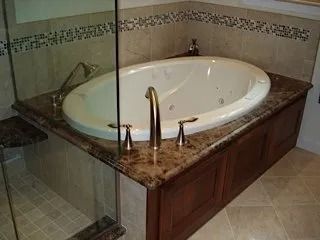 Bathroom with a corner jacuzzi tub, brown marble surround, glass shower, and beige tile floor