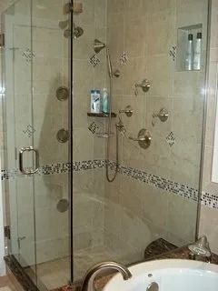 Glass shower enclosure with chrome fixtures and beige tiled walls in a bathroom