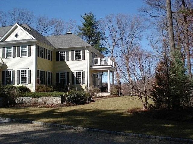 Two-story cream house with black shutters and a front porch on a sunny winter day