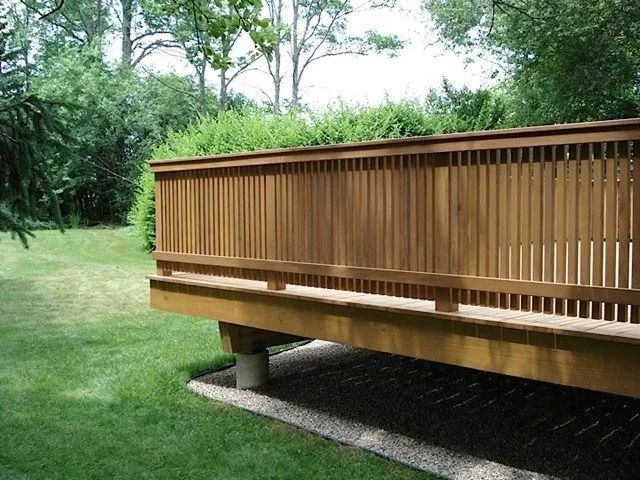 Wooden deck or walkway with railing in a grassy park setting