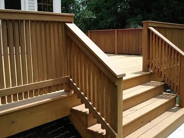 Wooden deck stairs with railings leading to a raised patio area outdoors