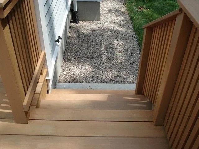 Wooden porch steps leading down to a gravel path beside a house.