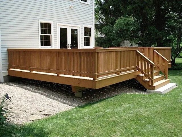 Wooden backyard deck attached to a house, with stairs and railing on the right