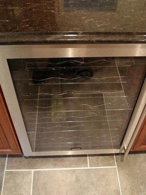 Stainless steel oven door beneath a countertop, with a wire rack visible through the glass.
