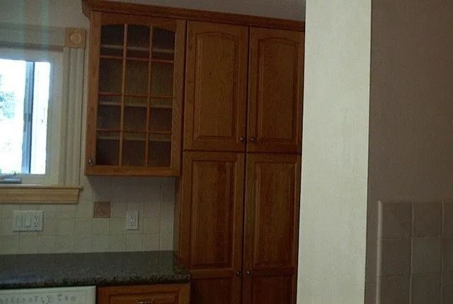 Kitchen with wooden cabinets, a window over the sink, and a countertop along the wall.