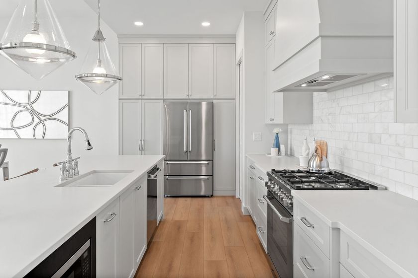 Bright modern kitchen with white cabinets, stainless appliances, island, and wood floor