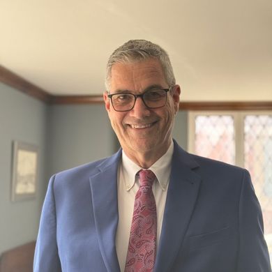 A man in a blue suit and red tie is smiling for the camera.