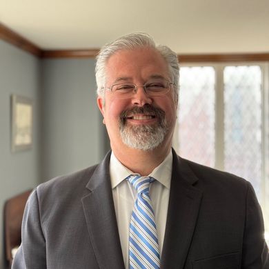 A man in a suit and tie is smiling for the camera.