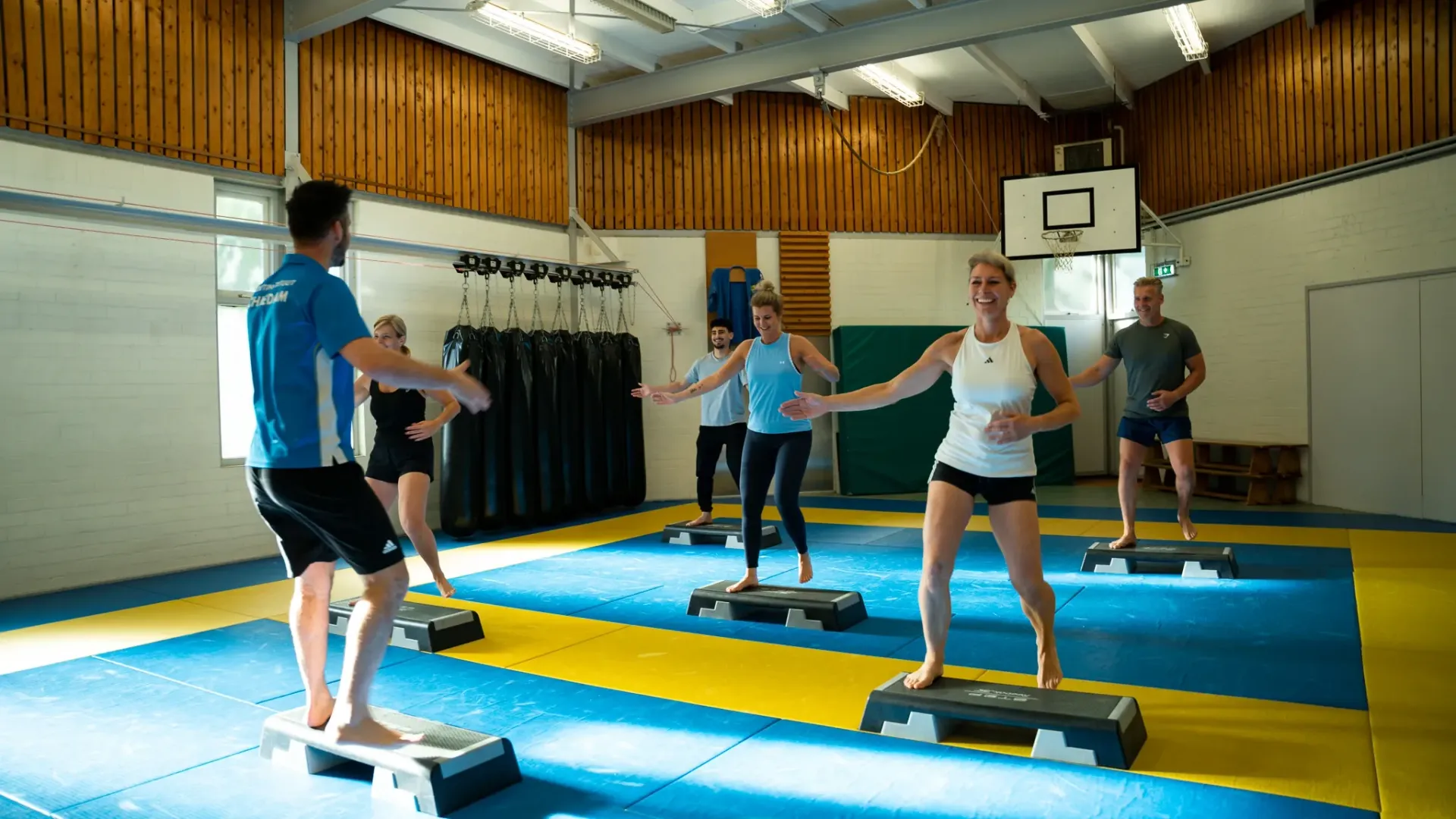 Een groep mensen doet stepaerobics in een sportschool.