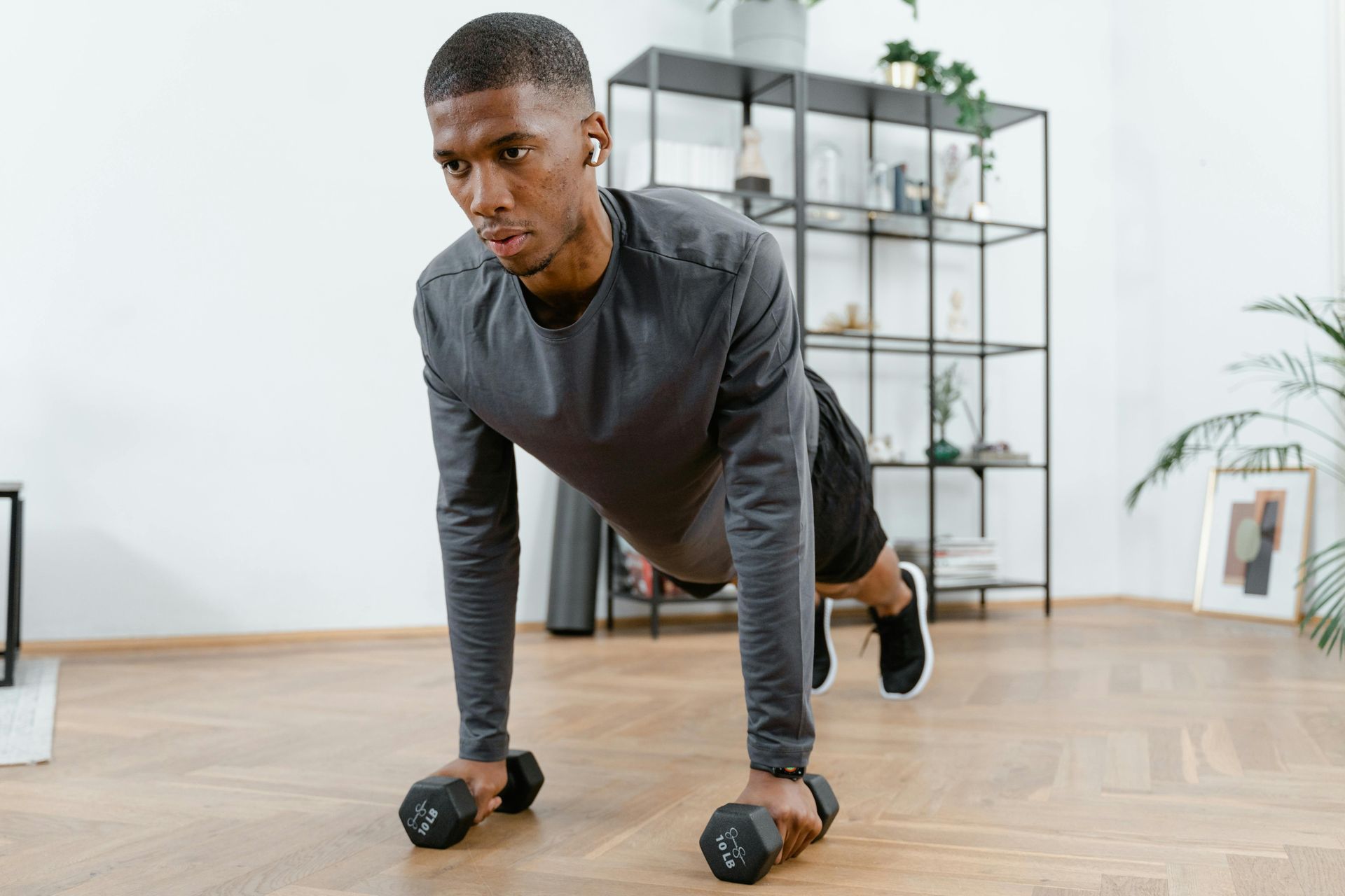 Een man doet push-ups met dumbbells in een woonkamer.