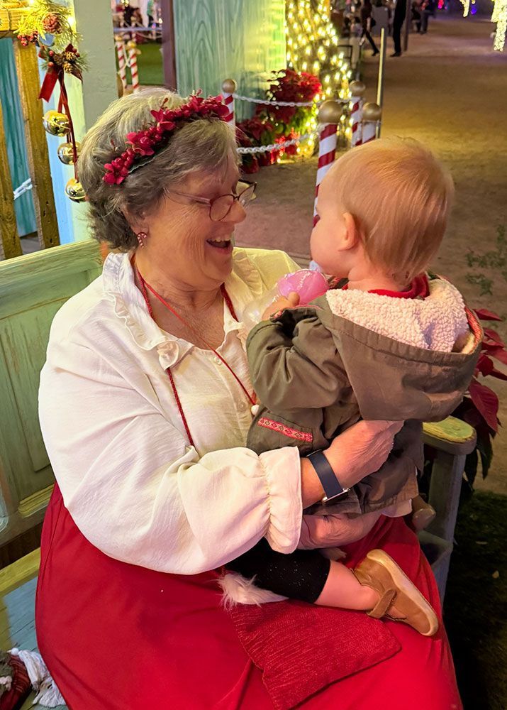 Mrs. Clause holds a young boy on her lap.