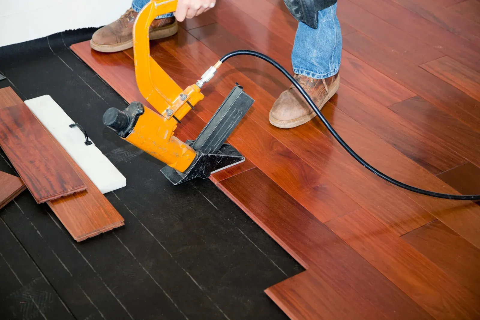 Installing hardwood flooring with a nail gun.