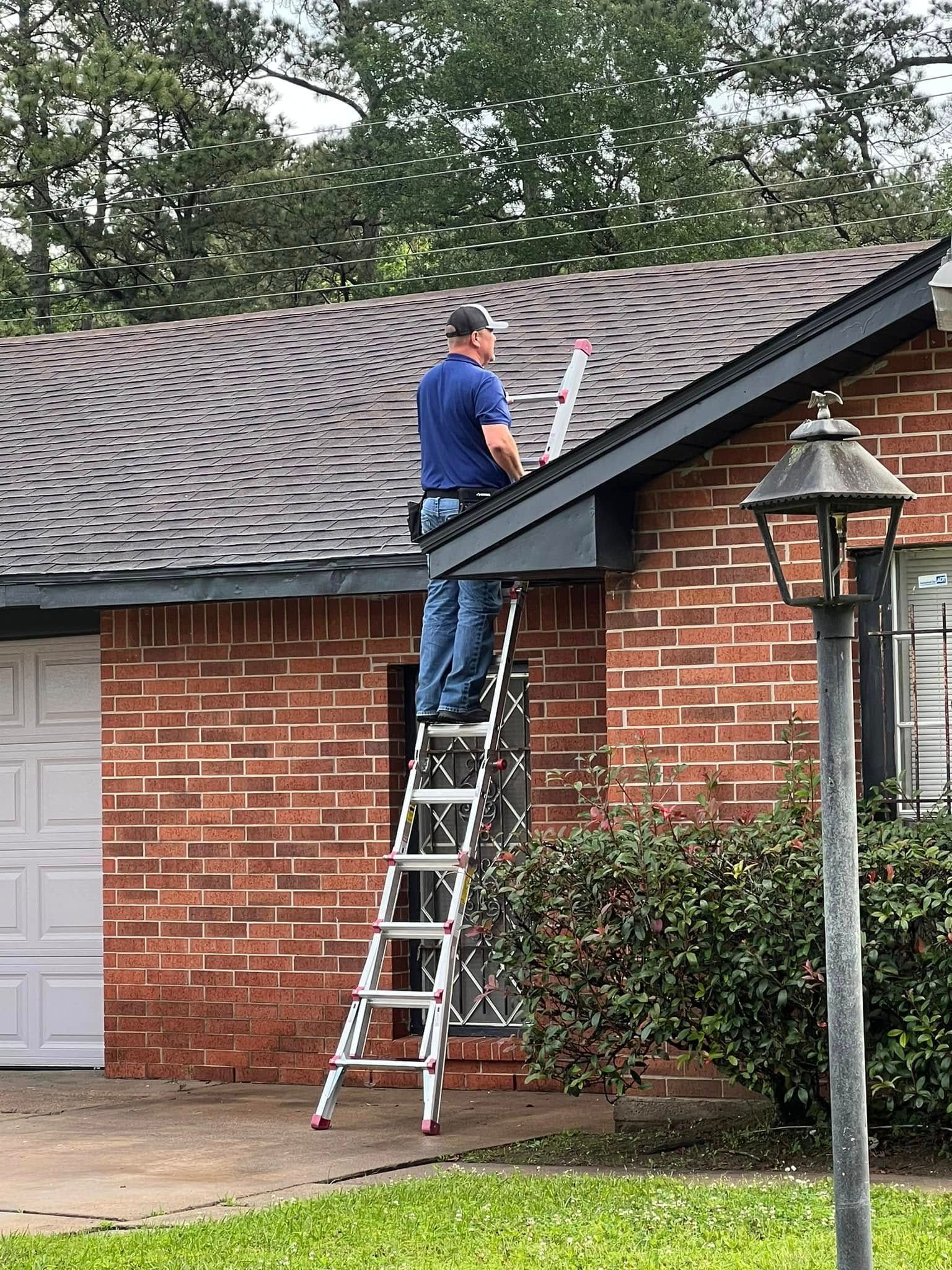 Worker on ladder repairing the roof edge of a brick house