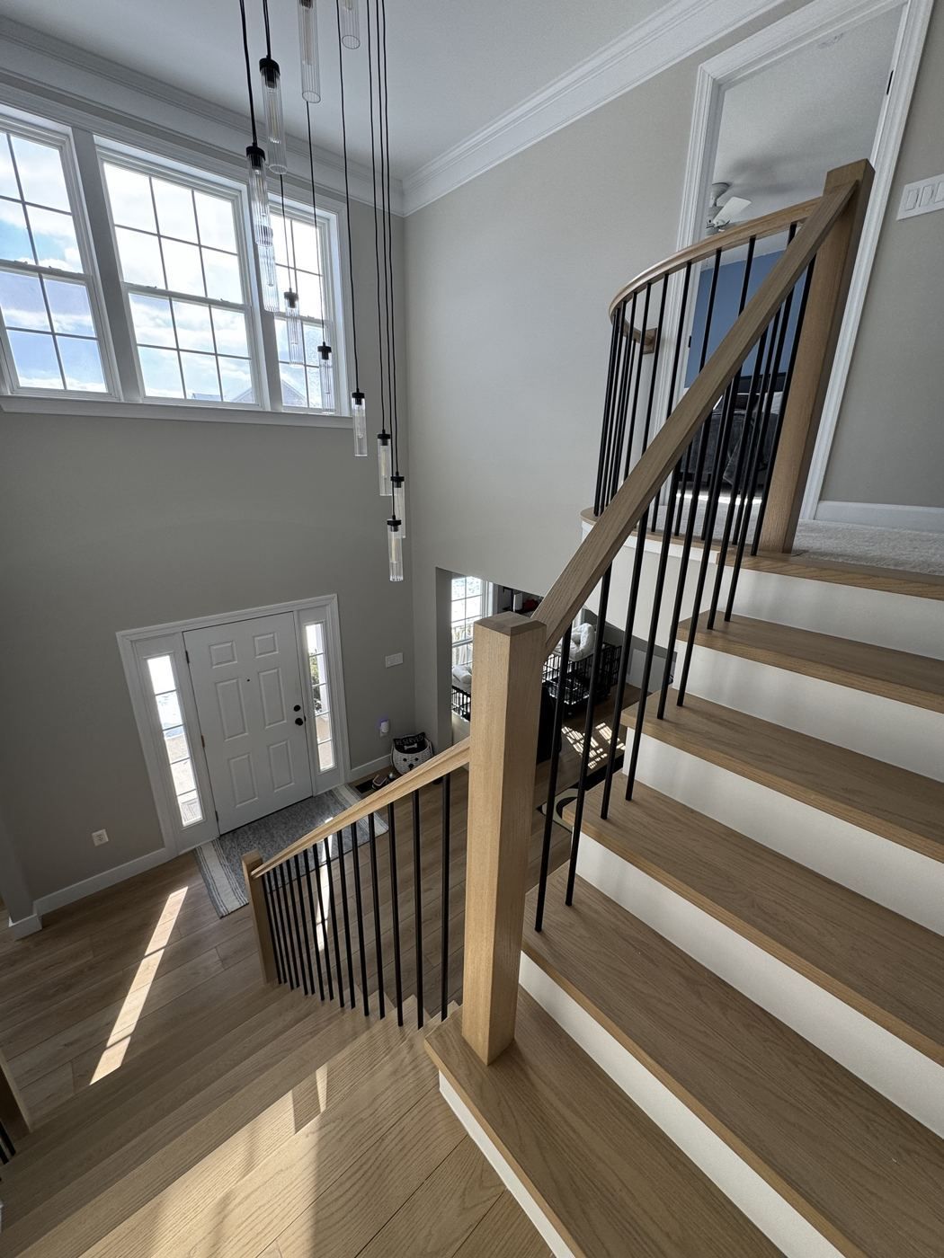Looking down a white oak stair under glass pendant lights