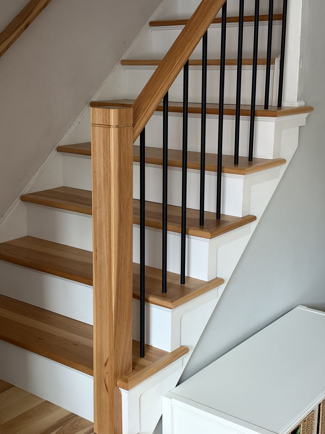 After: natural wood treads and box newel with round black balusters