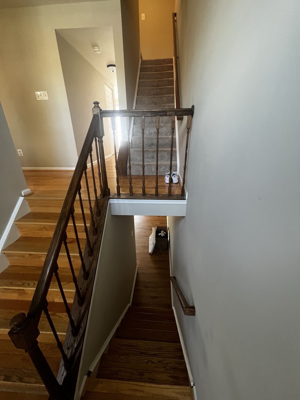 Before: dark stained railing and turned spindles at the landing, carpeted upper flight