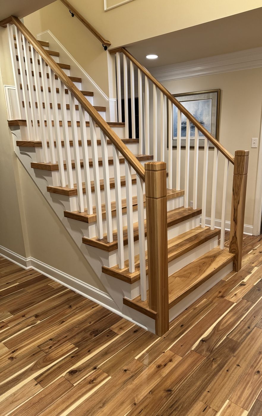 Natural wood stair with white balusters over new hardwood floors
