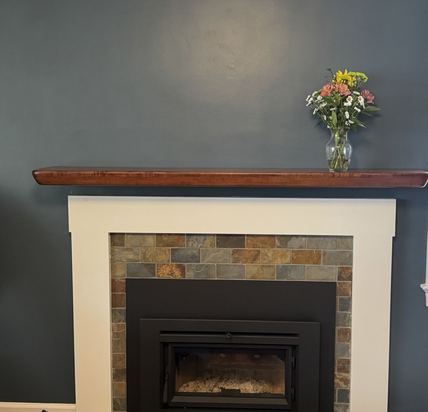 Floating wood mantel over a white fireplace surround