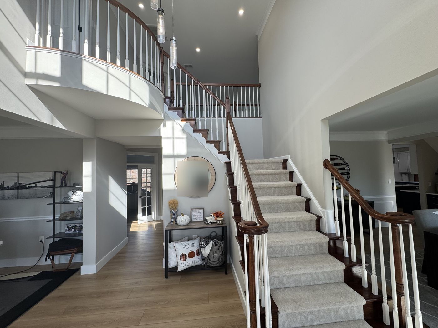 Before: two-story foyer with curved balcony, dark rail, spindles and carpeted stair